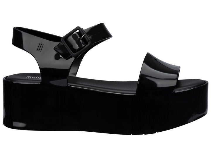 Sandalia Melissa de plataforma alta en color negro brillante con correa ajustable al tobillo.