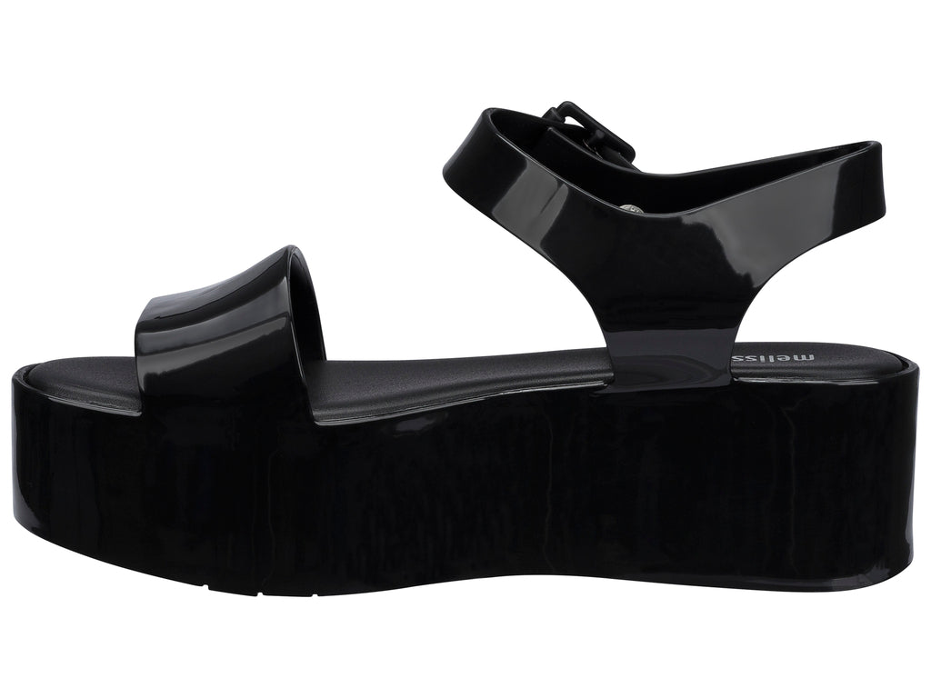 Sandalia Melissa de plataforma alta en color negro brillante con correa ajustable al tobillo.