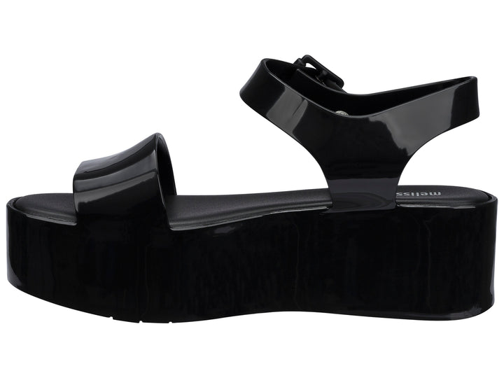 Sandalia Melissa de plataforma alta en color negro brillante con correa ajustable al tobillo.