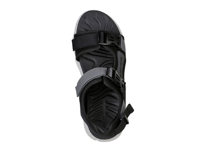 Sandalia deportiva Skechers en color negro y gris con suela blanca moteada y correas ajustables.
