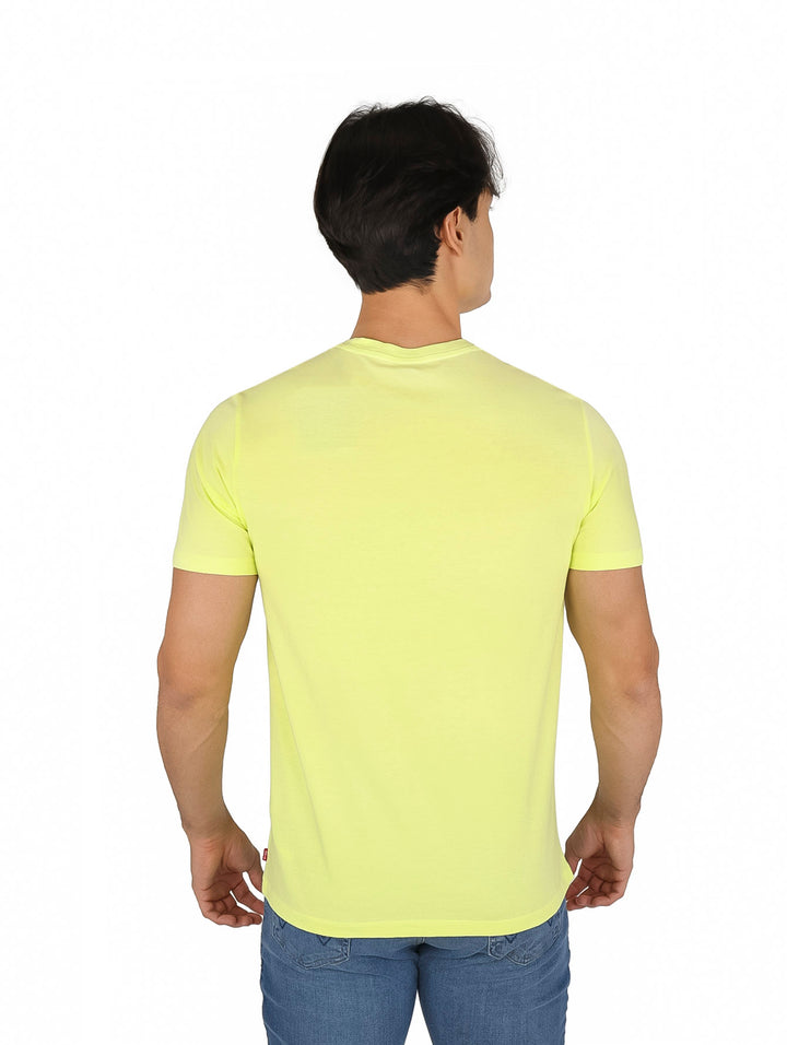 Hombre vistiendo una camiseta verde lima con estampado gráfico de animales y jeans azules.
