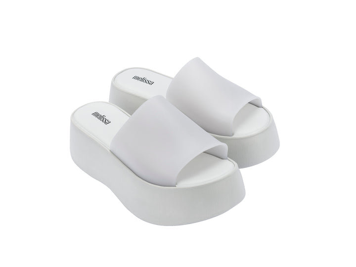 Par de sandalias Melissa blancas con plataforma alta y diseño minimalista de una sola banda.