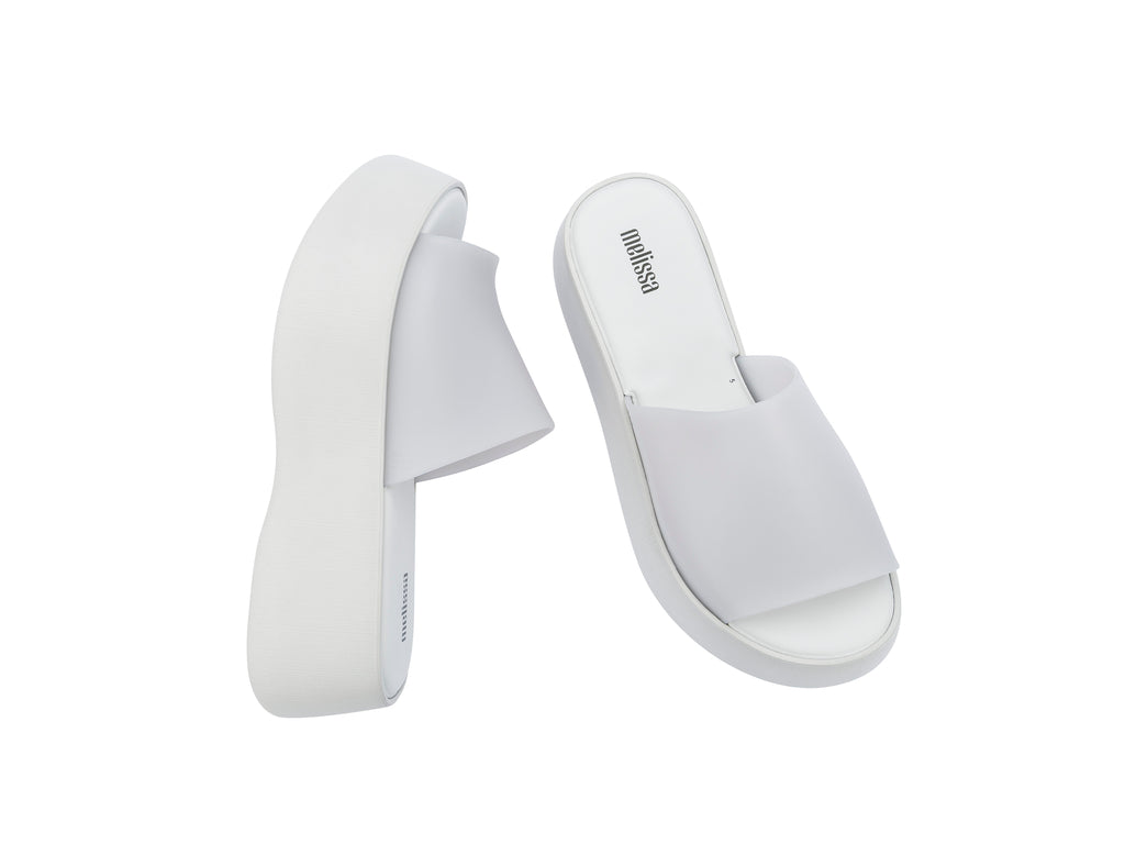 Par de sandalias Melissa blancas con plataforma alta y diseño minimalista de una sola banda.