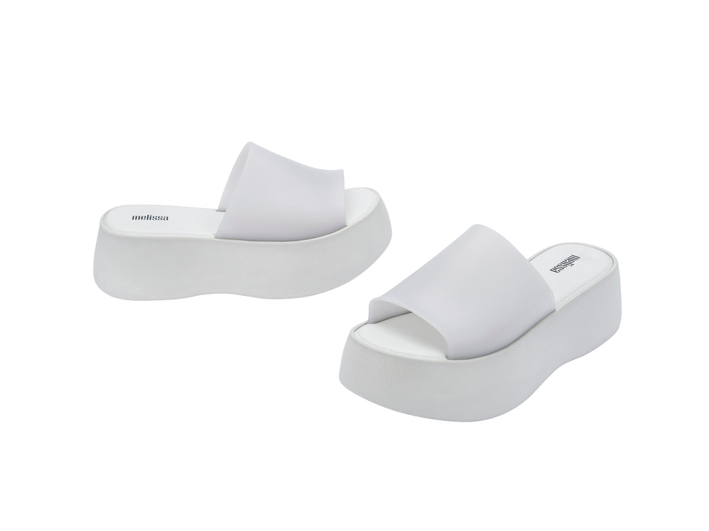 Par de sandalias Melissa blancas con plataforma alta y diseño minimalista de una sola banda.