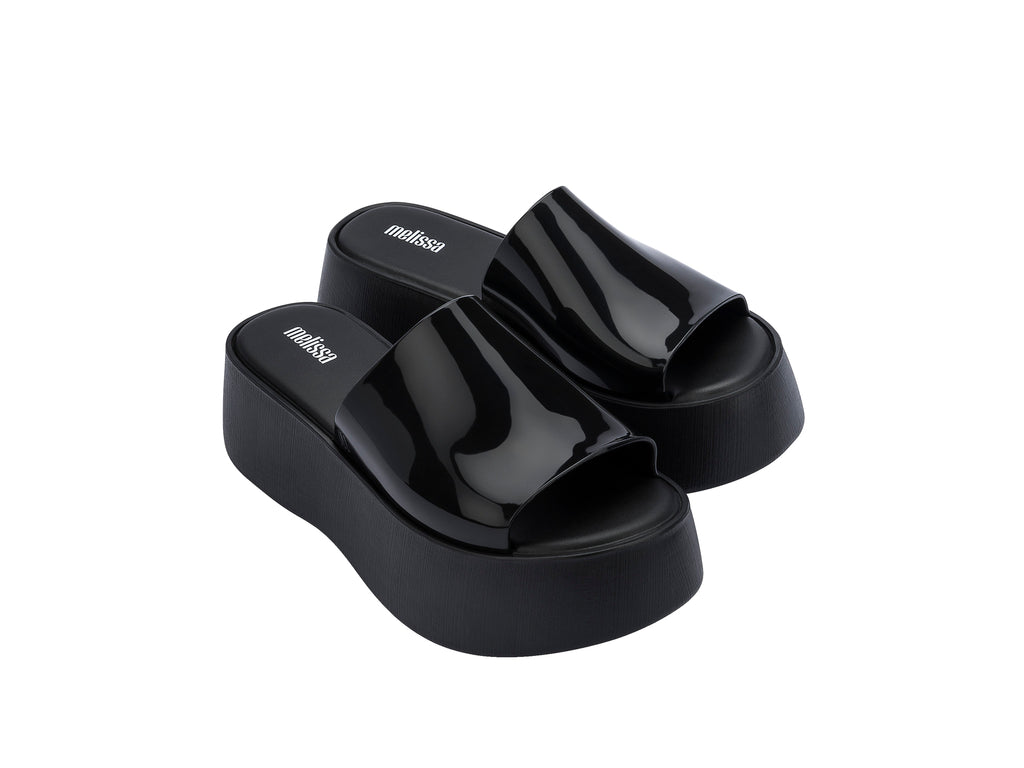 Sandalias negras de plataforma con correa brillante y suela gruesa mate.