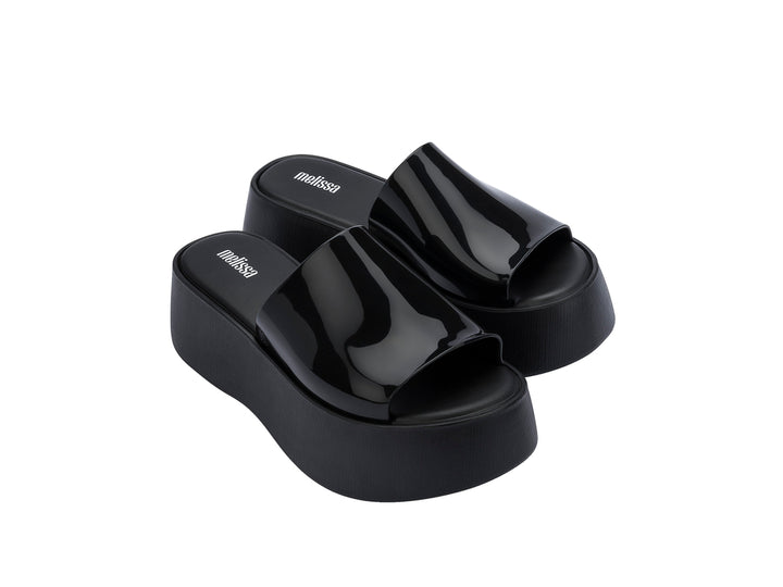Sandalias negras de plataforma con correa brillante y suela gruesa mate.