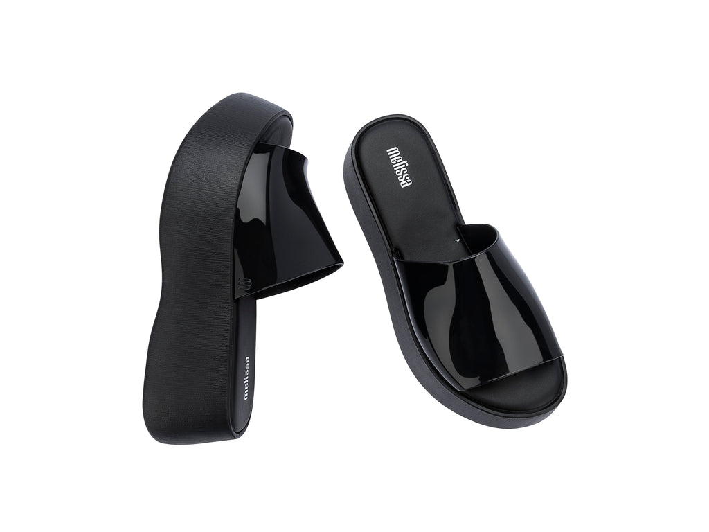 Sandalias negras de plataforma con correa brillante y suela gruesa mate.