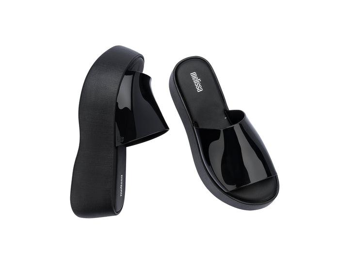Sandalias negras de plataforma con correa brillante y suela gruesa mate.