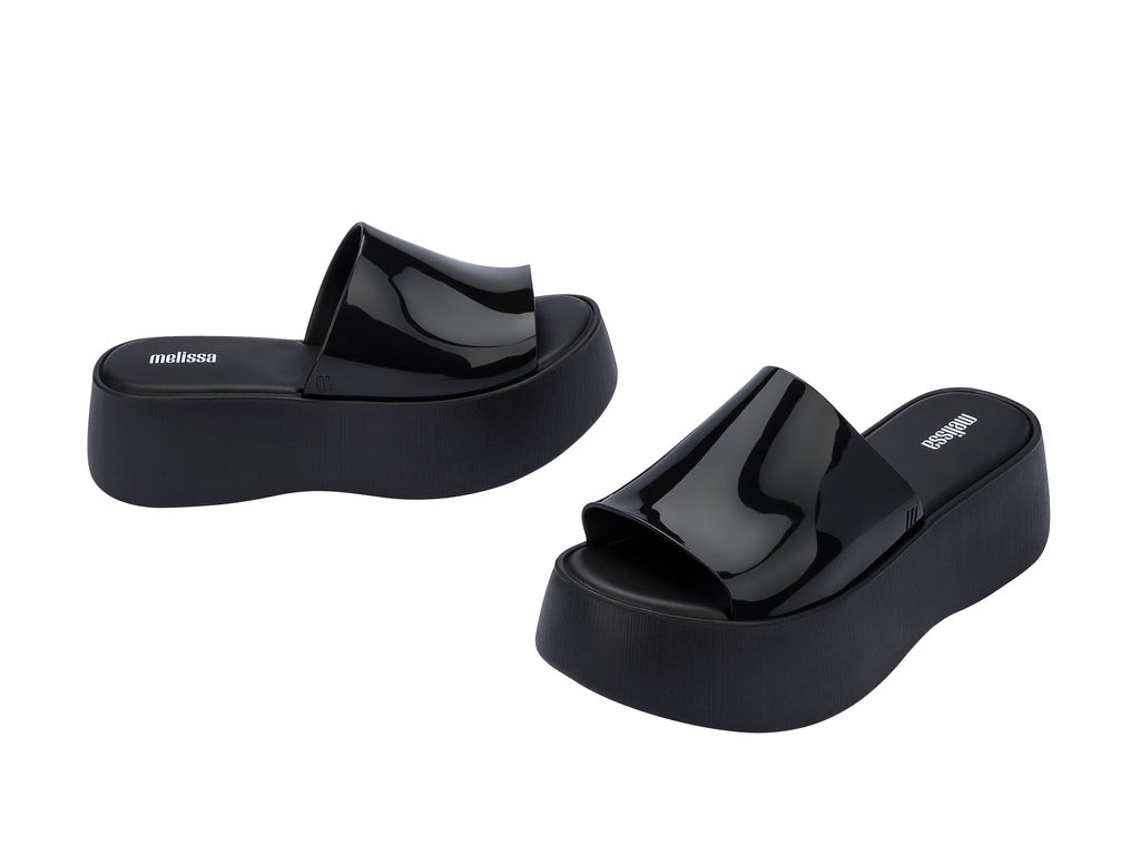 Sandalias negras de plataforma con correa brillante y suela gruesa mate.