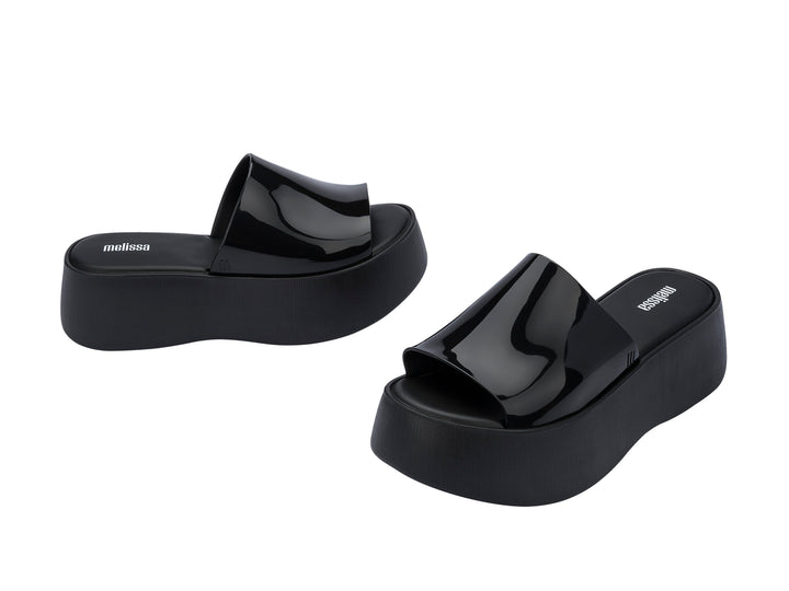 Sandalias negras de plataforma con correa brillante y suela gruesa mate.
