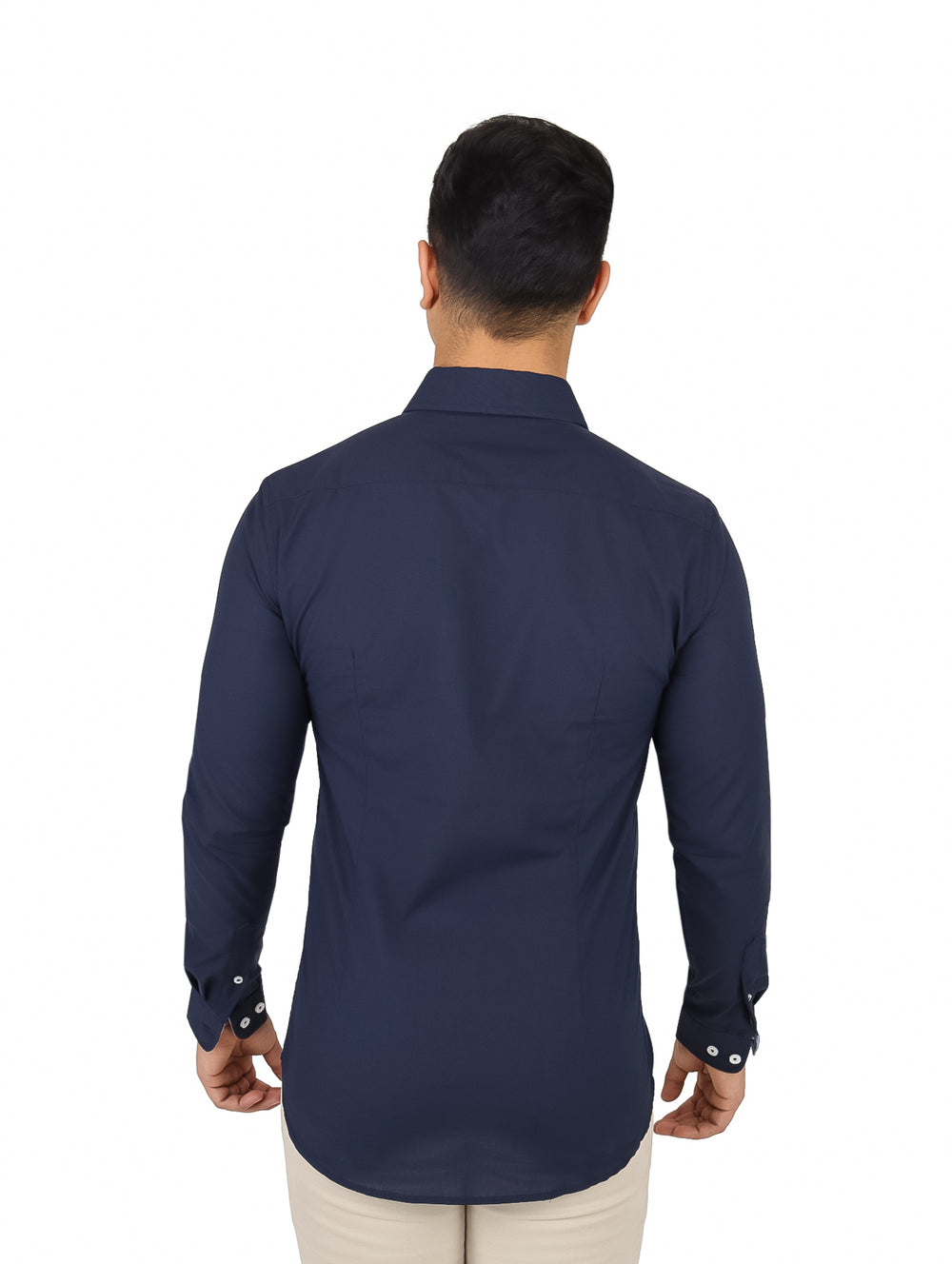 Hombre vistiendo una camisa de manga larga color azul marino con botones frontales y pantalones beige.