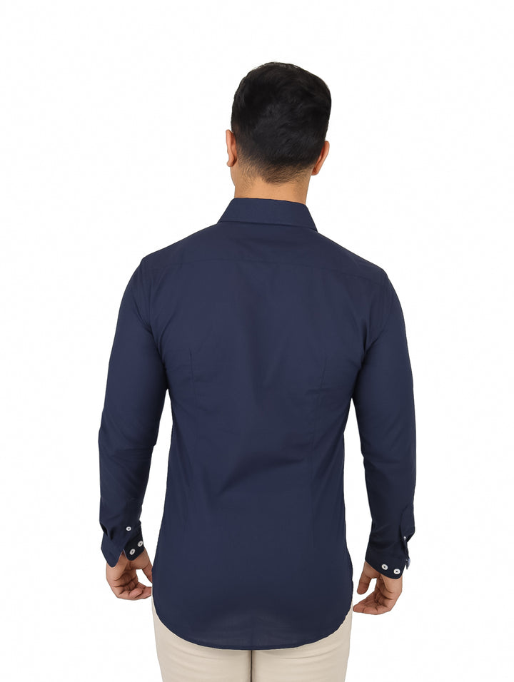 Hombre vistiendo una camisa de manga larga color azul marino con botones frontales y pantalones beige.