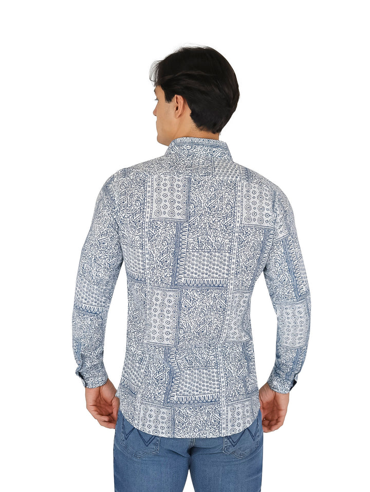Hombre vistiendo camisa blanca de manga larga con estampados azules y pantalones vaqueros azules.