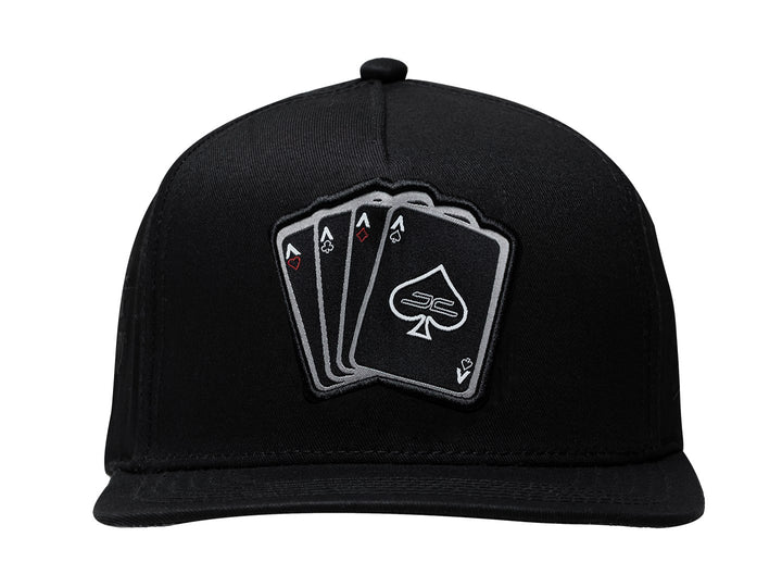 Gorra negra JC HATS con visera plana y un bordado frontal de cuatro cartas de póker.