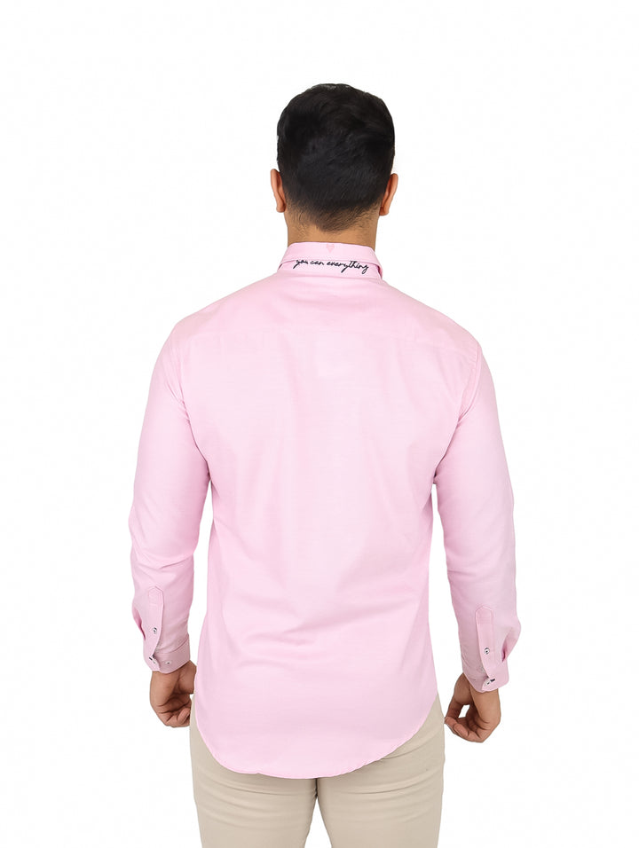 Hombre vistiendo una camisa de manga larga color rosa claro con cuello y botones frontales.