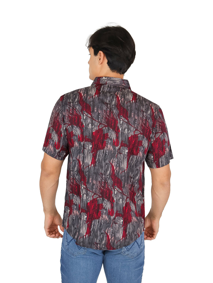Hombre vistiendo una camisa de manga corta con estampado abstracto en colores rojo y gris.