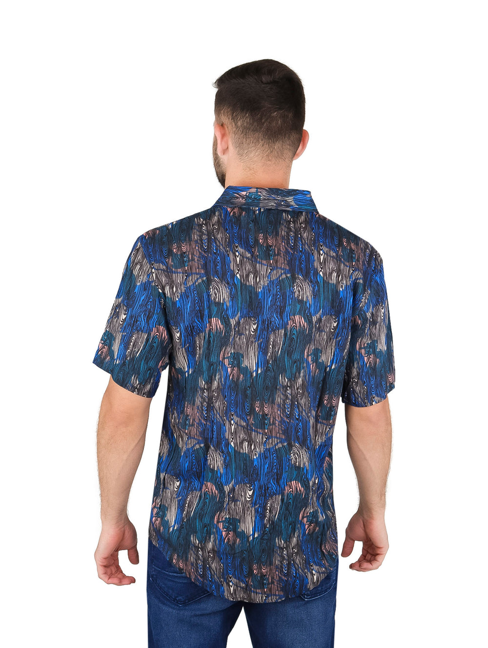 Hombre vistiendo camisa de manga corta azul con estampado abstracto y pantalones vaqueros.
