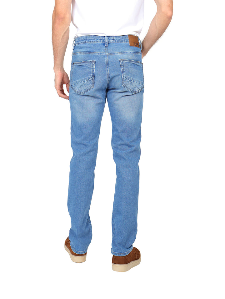 Hombre vistiendo pantalones jeans de mezclilla color azul claro con corte recto y calzado café.