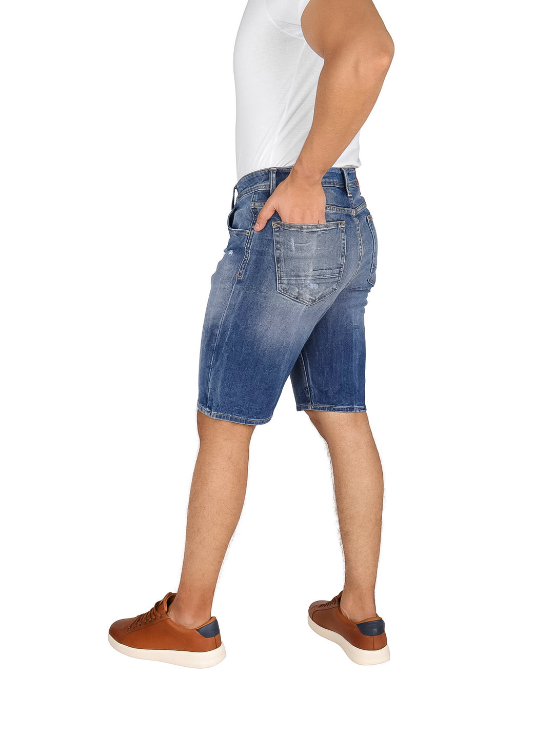 Hombre vistiendo bermudas de mezclilla azul con efecto de lavado stone y tenis color café.