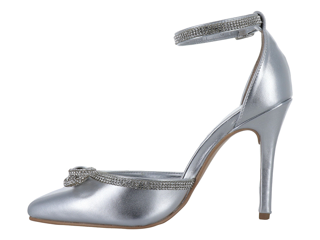 Zapato de tacón alto color plata con punta cerrada, moño decorativo y correa al tobillo con detalles brillantes.