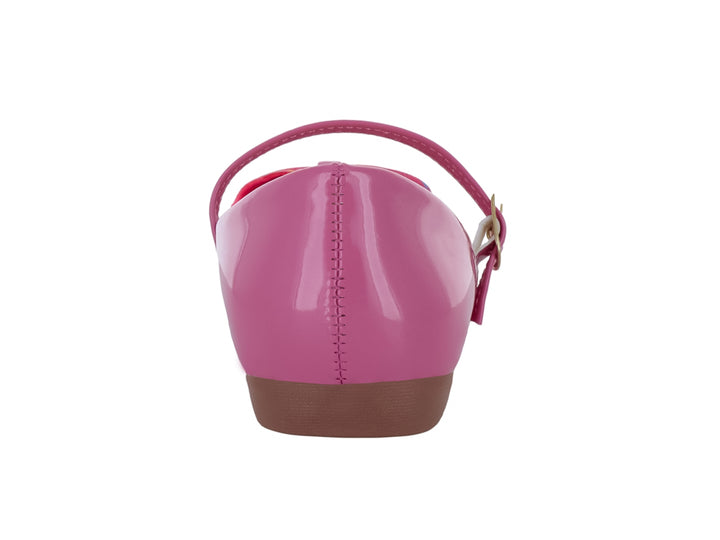 Zapato plano fucsia brillante para niña con moño decorativo y correa ajustable.