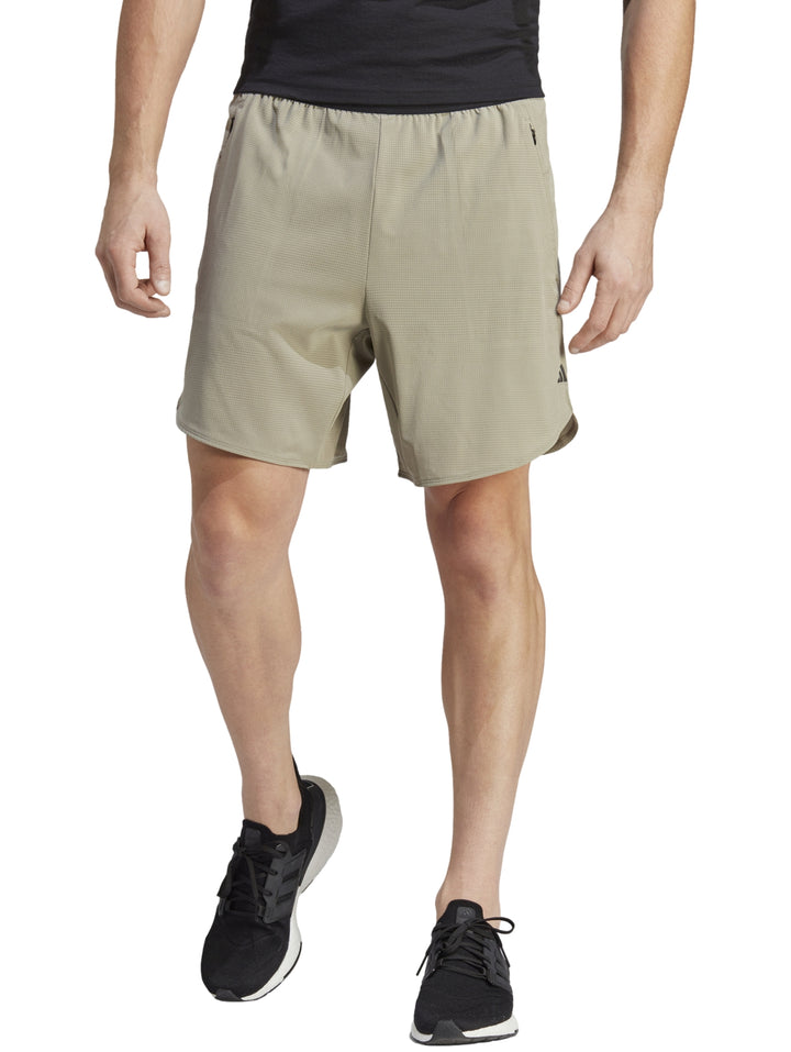 Hombre usando shorts deportivos Adidas color beige claro con tenis negros.