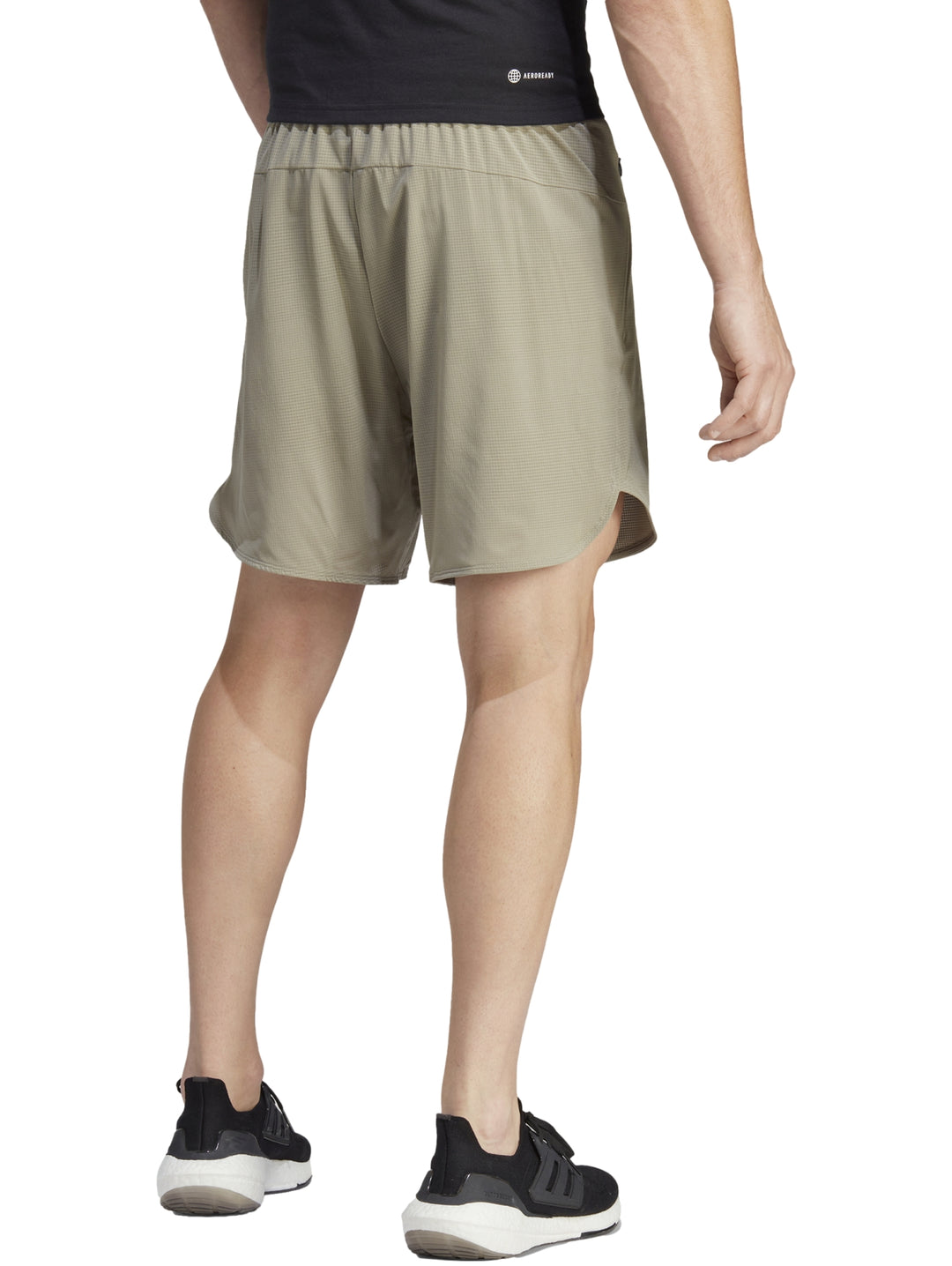 Hombre usando shorts deportivos Adidas color beige claro con tenis negros.