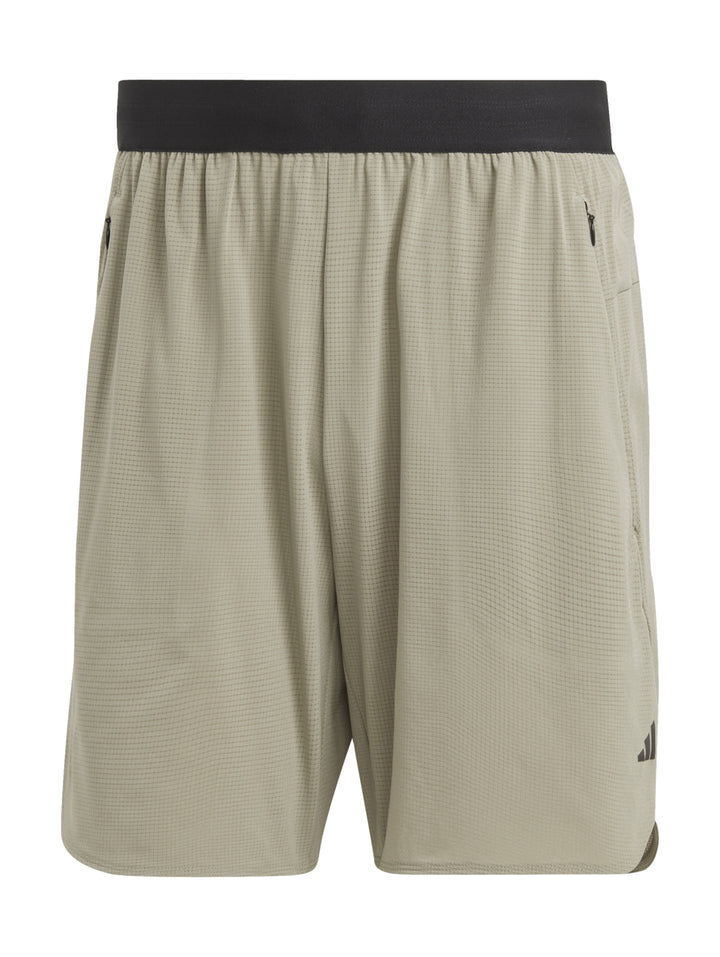 Hombre usando shorts deportivos Adidas color beige claro con tenis negros.