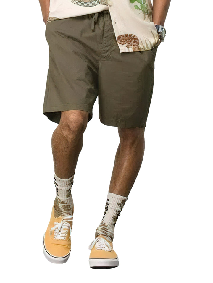 Hombre usando pantalones cortos de surf color verde oliva marca Vans.