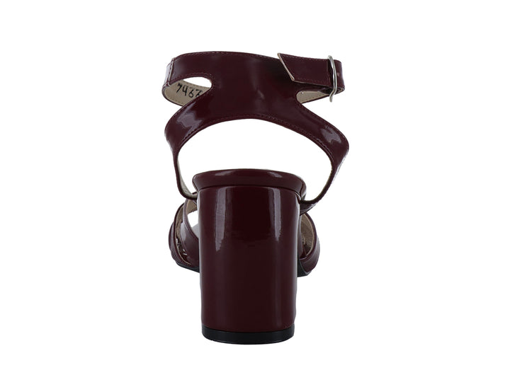 Sandalia color vino con acabado brillante en charol, tacón cuadrado y correa al tobillo.