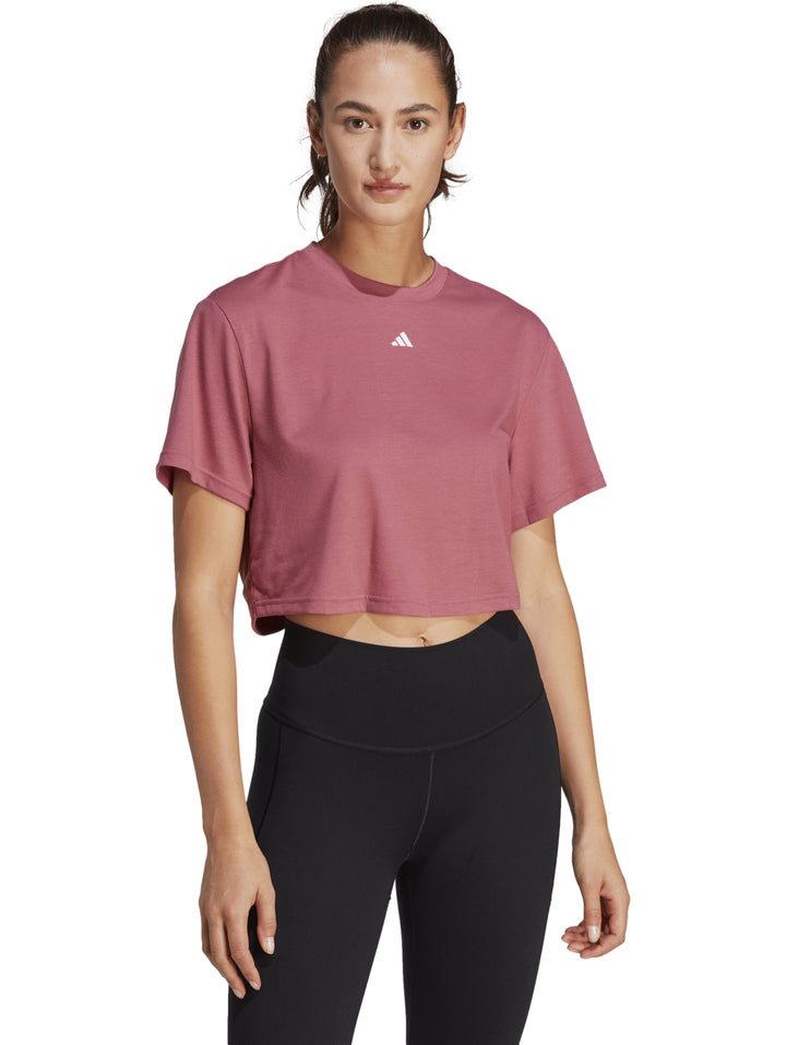 Mujer usando camiseta corta rosa Adidas y leggings negros.