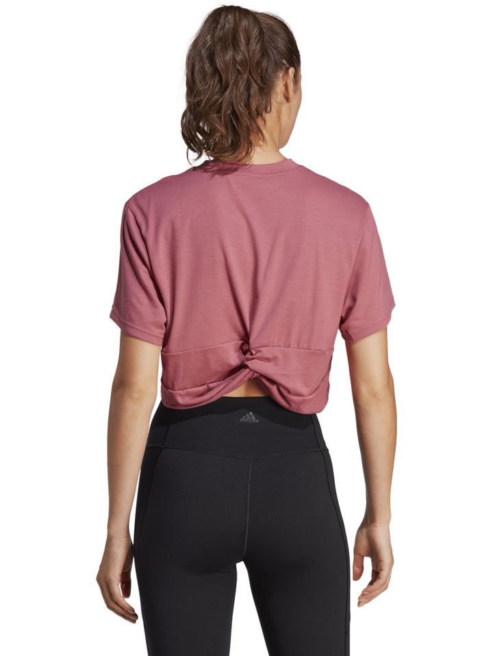 Mujer usando camiseta corta rosa Adidas y leggings negros.