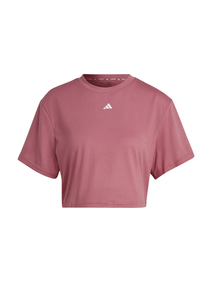 Mujer usando camiseta corta rosa Adidas y leggings negros.