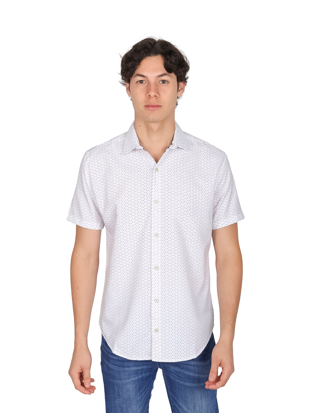 Hombre vistiendo una camisa blanca de manga corta con estampado de puntos pequeños y pantalones azules.