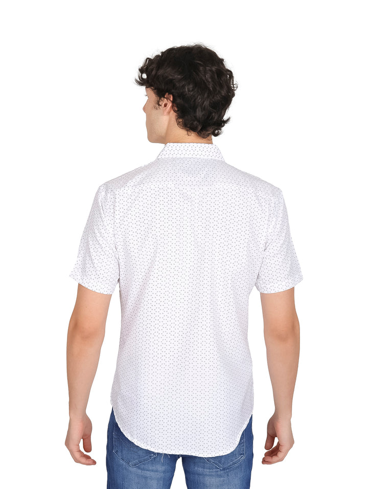 Hombre vistiendo una camisa blanca de manga corta con estampado de puntos pequeños y pantalones azules.