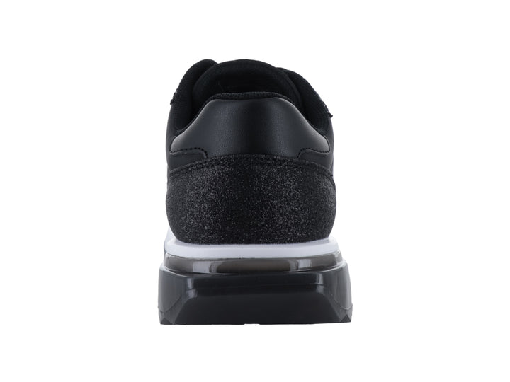 Tenis negros Guess con acabado brillante y suela blanca.