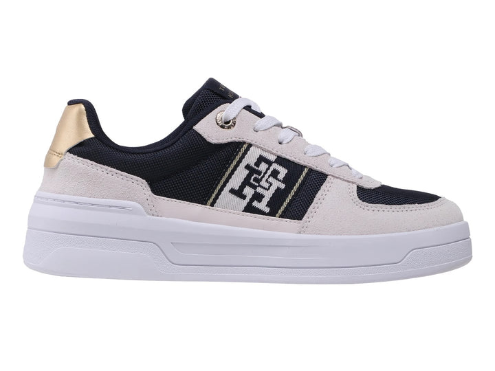 Tenis Tommy Hilfiger color azul marino y beige con suela blanca y detalles dorados en el talón.