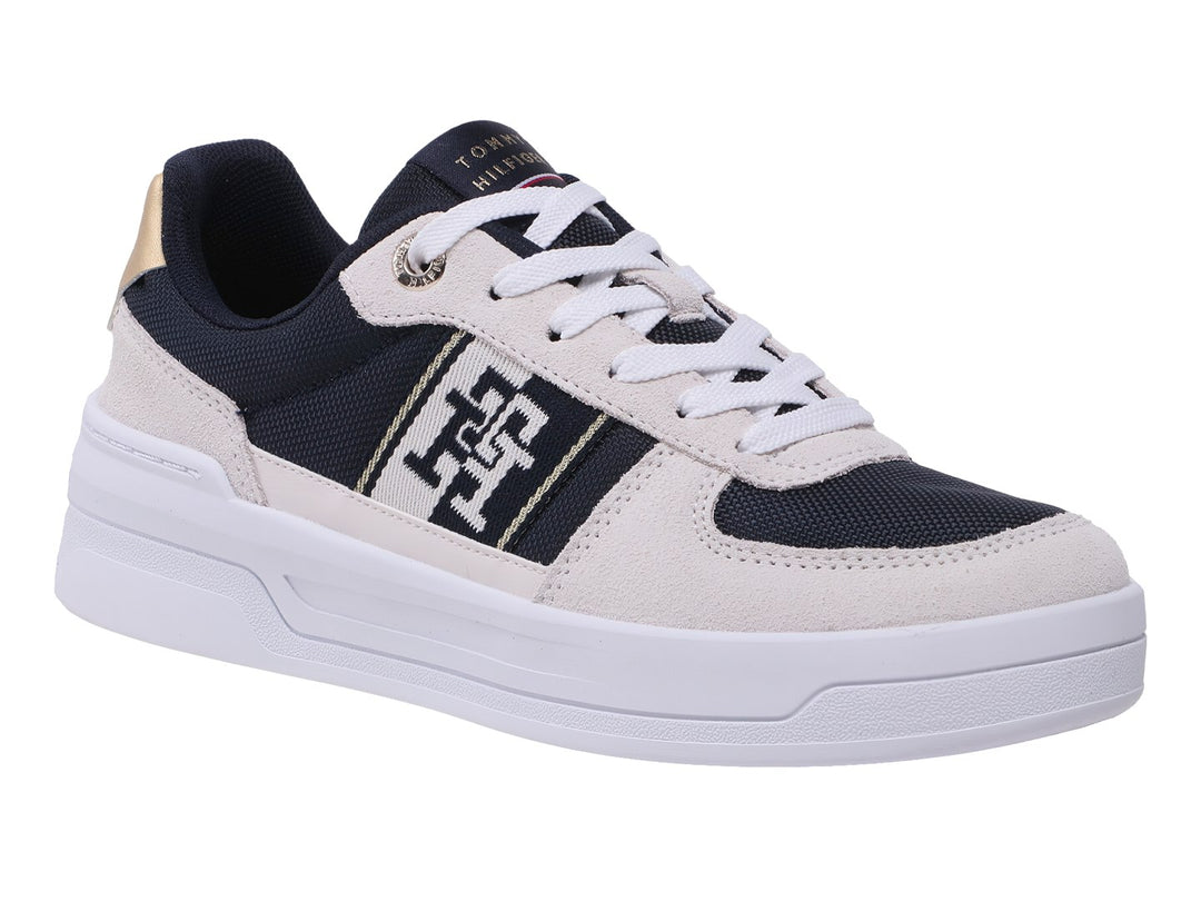 Tenis Tommy Hilfiger color azul marino y beige con suela blanca y detalles dorados en el talón.