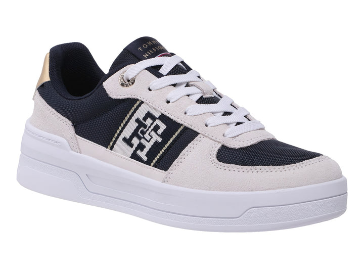 Tenis Tommy Hilfiger color azul marino y beige con suela blanca y detalles dorados en el talón.