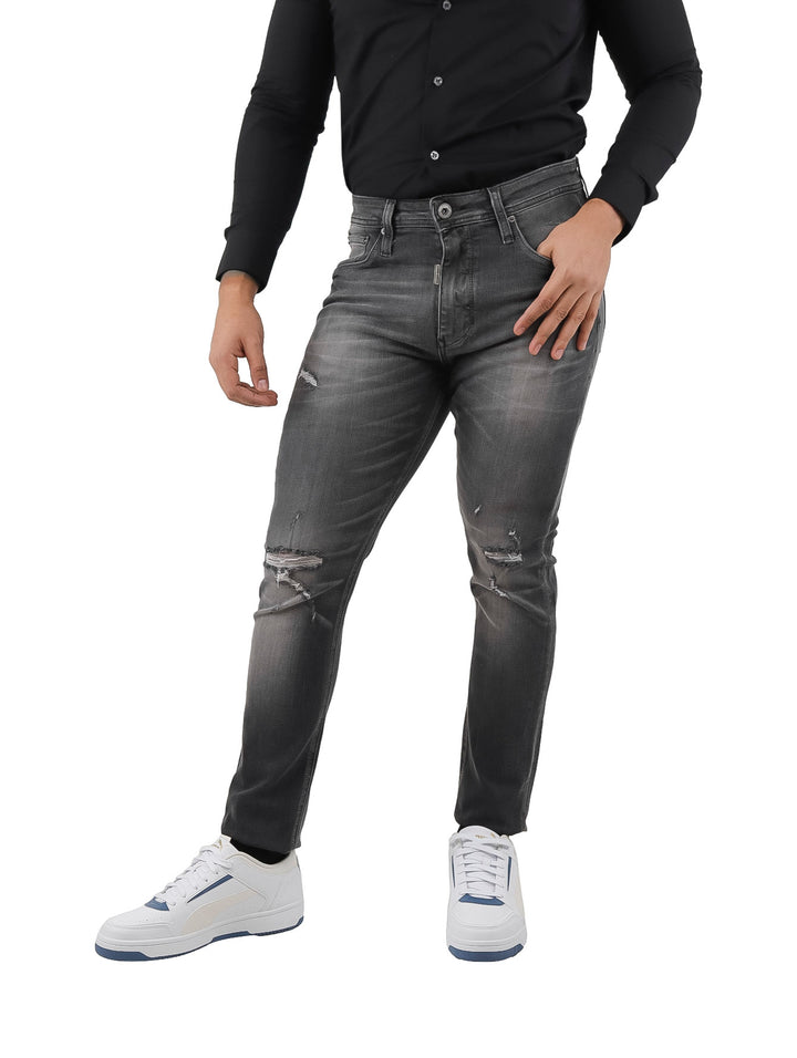 Hombre vistiendo jeans negros con efecto de destrucción y lavado.
