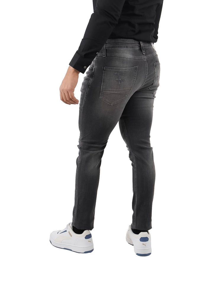Hombre vistiendo jeans negros con efecto de destrucción y lavado.