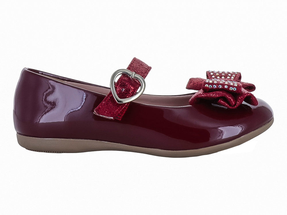 Zapato plano color vino de charol para niña con moño brillante y hebilla en forma de corazón.