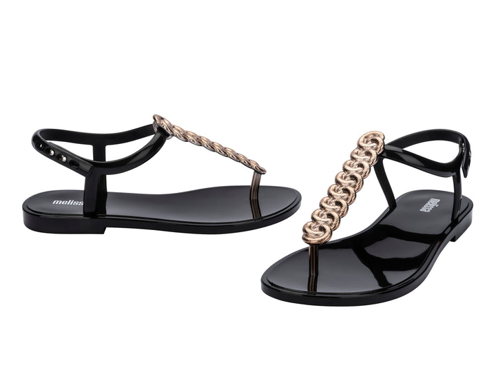Sandalias negras Melissa con detalle de cadena de strass dorado y correa al tobillo.