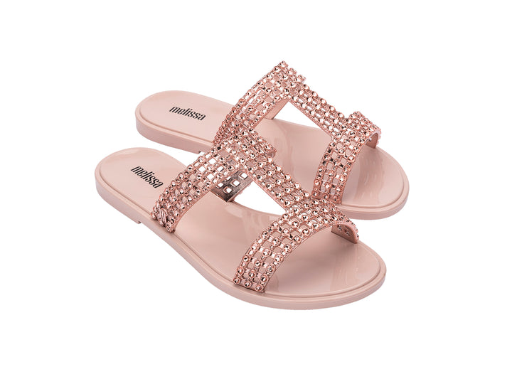 Sandalias Melissa Glowing Slide en color rosa con tiras decoradas con brillantes y suela plana.