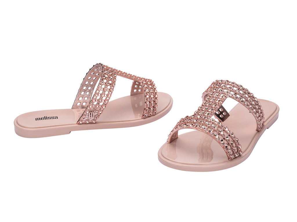 Sandalias Melissa Glowing Slide en color rosa con tiras decoradas con brillantes y suela plana.