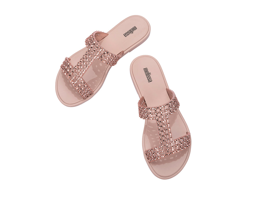 Sandalias Melissa Glowing Slide en color rosa con tiras decoradas con brillantes y suela plana.
