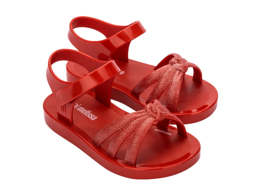 Sandalia infantil Mini Melissa de color rojo con tiras frontales brillantes y correa ajustable.