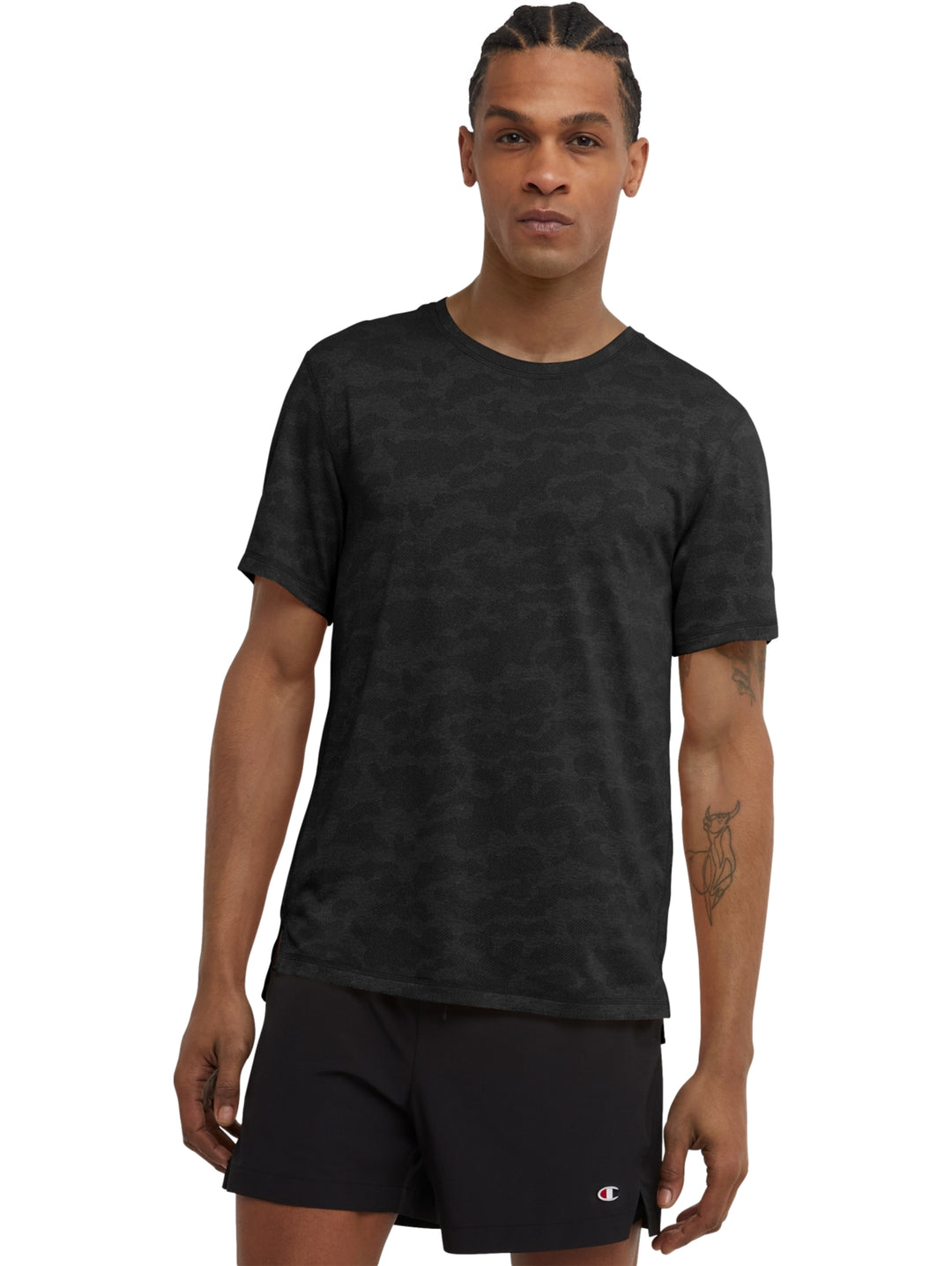 Hombre vistiendo una camiseta Champion de manga corta en color negro con estampado de camuflaje jacquard.
