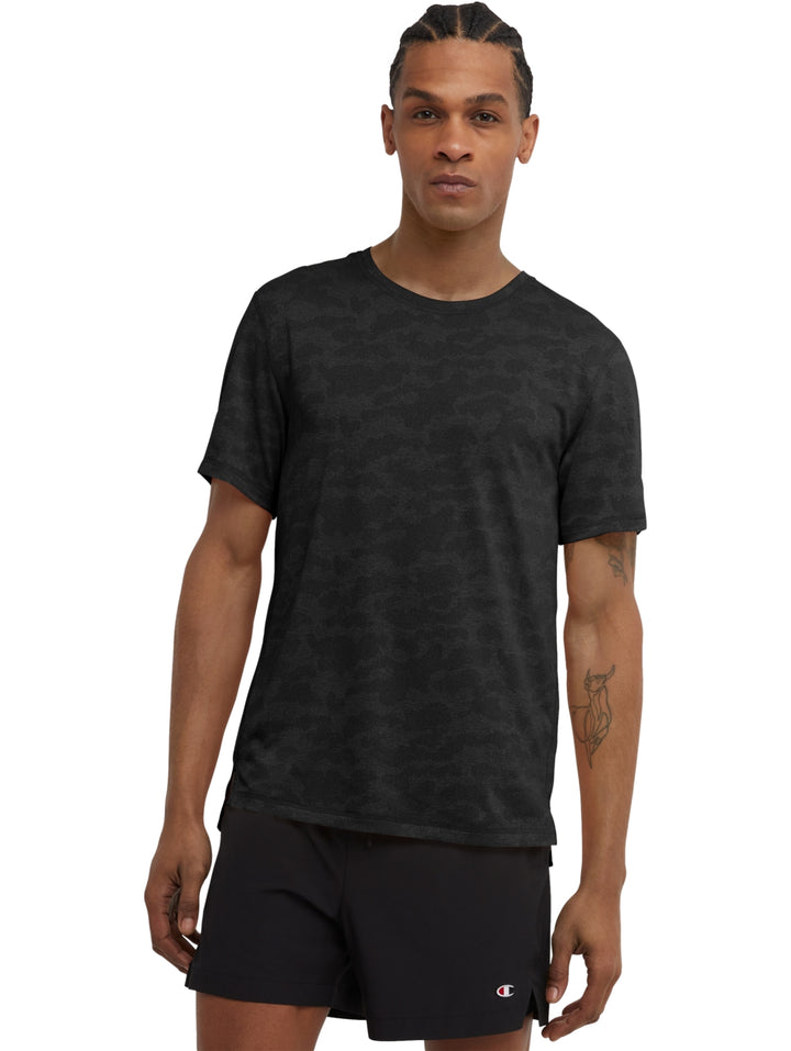 Hombre vistiendo una camiseta Champion de manga corta en color negro con estampado de camuflaje jacquard.