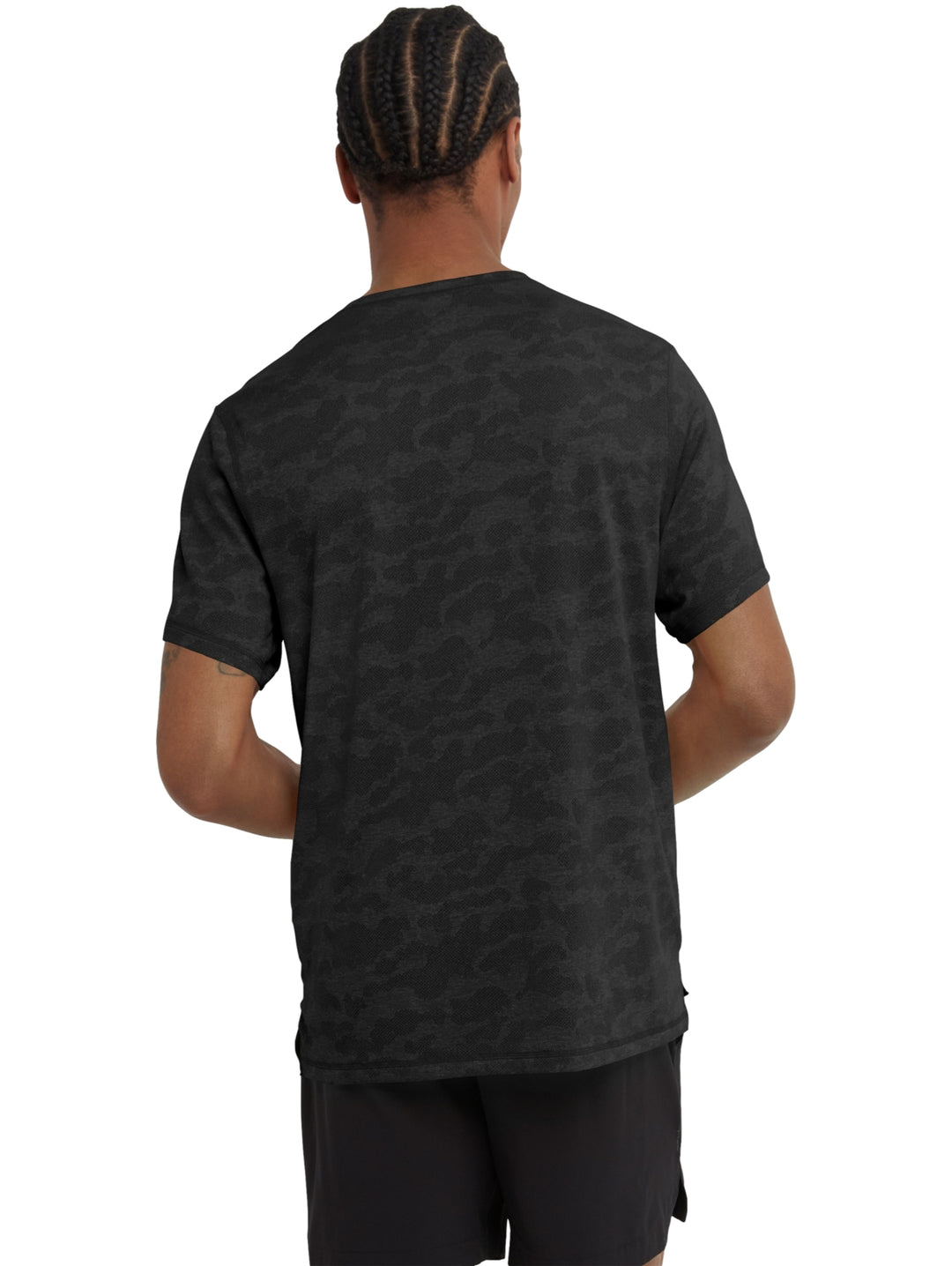 Hombre vistiendo una camiseta Champion de manga corta en color negro con estampado de camuflaje jacquard.